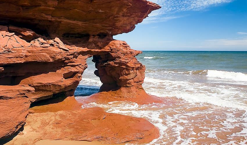 Waves break near a sea arch of coast of Prince Edward Island.