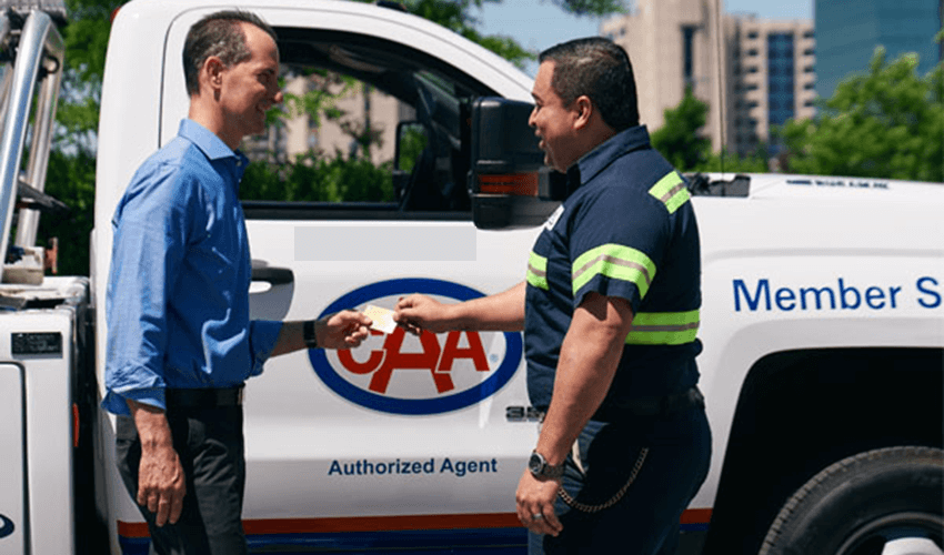 A customer and CAA technician pass a CAA membership in from of a tool truck. 