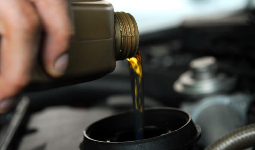 Close-up filling car oil under hood.