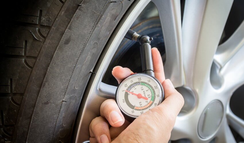 Close-up of hand examining air pressure in tire.