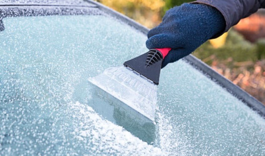 Close-up scraping ice off windshield.