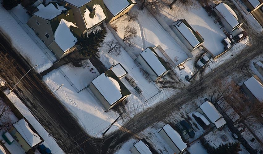 Aerial view of houses with snow covering roof tops. 