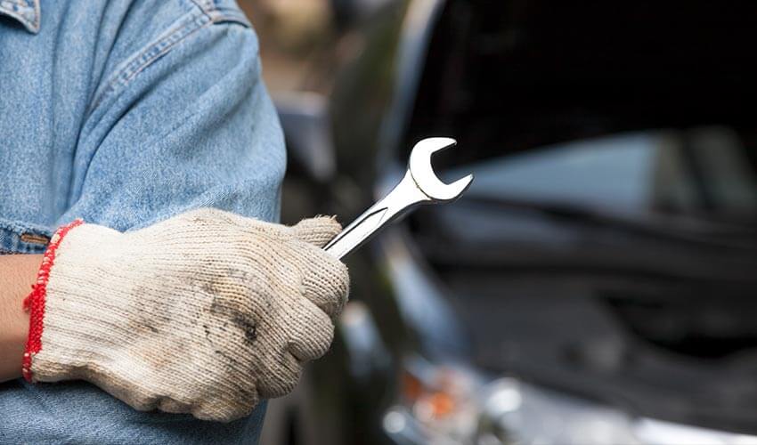 A mechanic holding a  wrench.