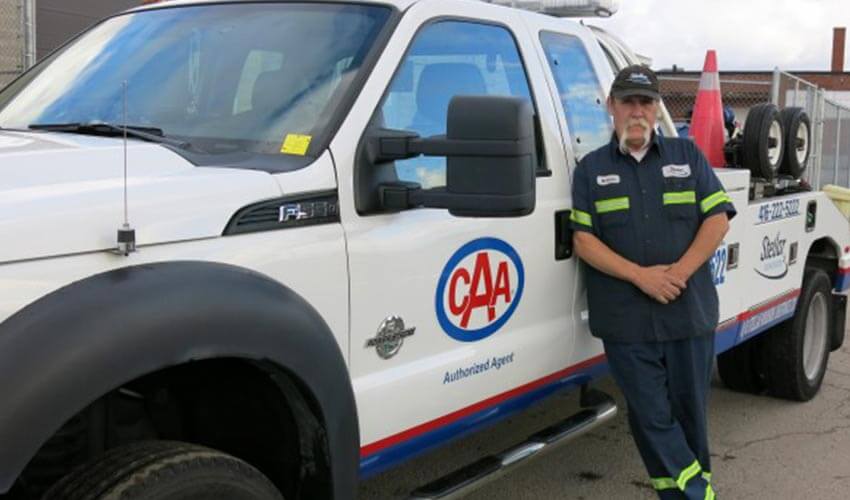 Bill stands next to CAA tow truck.