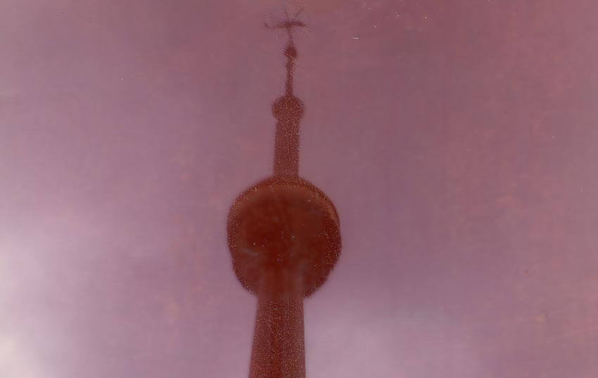 An old photograph of the CN Tower with a helicopter in the sky.