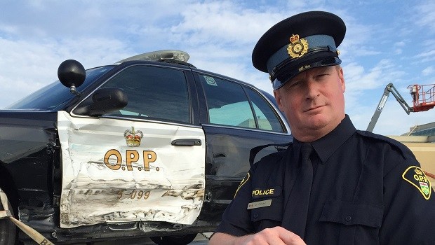 A police officer standing next to a damaged police vehicle.