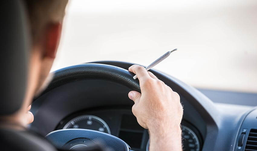 Man driving and smoking joint