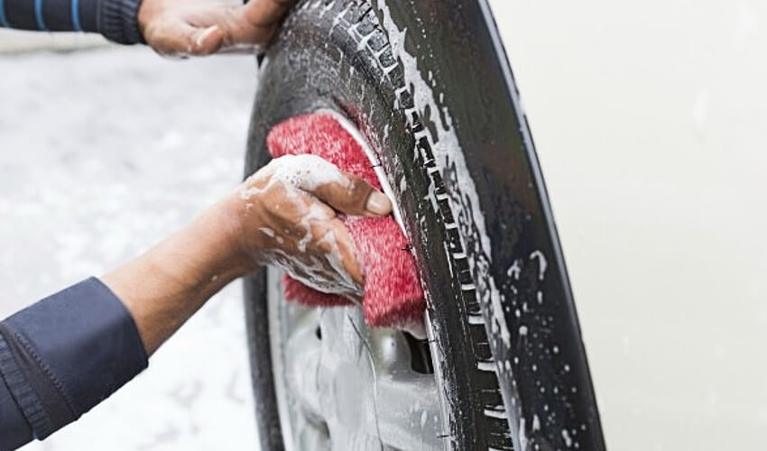 Close up hand washing tires with soap.