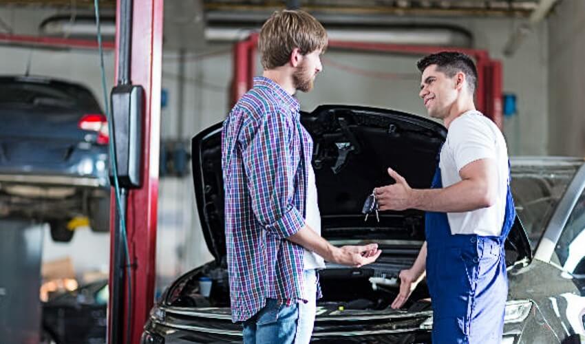 Mechanic handing keys back to car owner.