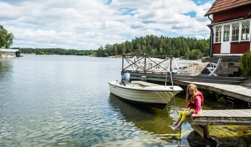 A young girl sitting on the docks on the lake.