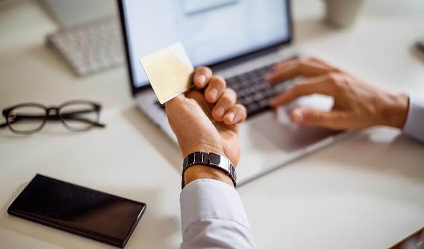 Close up of a man entering information online with credit card.