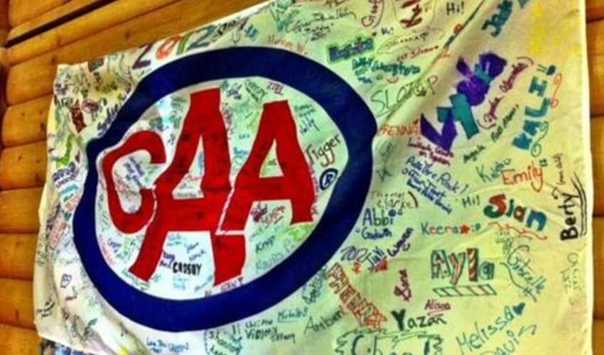 CAA flag with student signatures hanging on a wall.