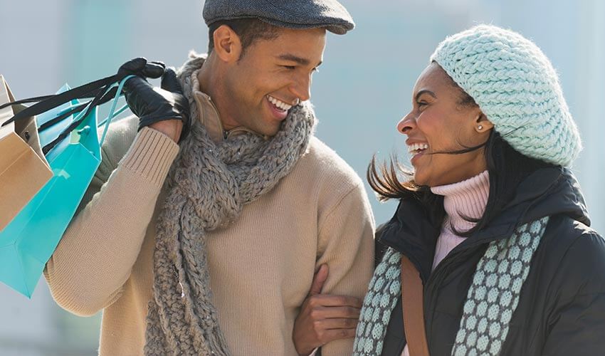 A black couple happily shopping in winter.