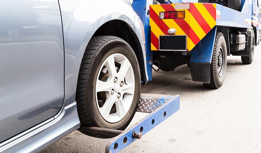 Close up of a tow truck towing a silver car.