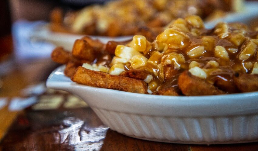 Close-up of poutine fries, cheese curds and gravy in a bowl.
