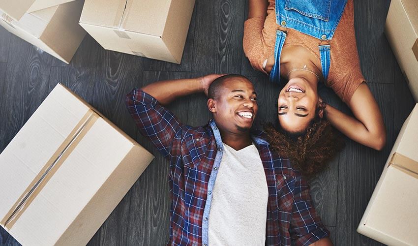 An attractive young couple moving into new house, lying on the floor among moving boxes.
