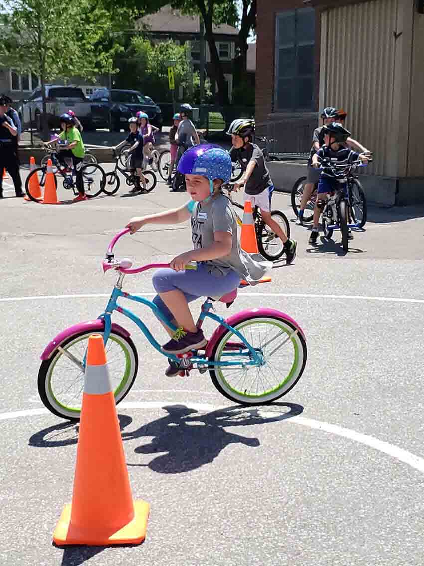 Kid learning bike safety in school yard.