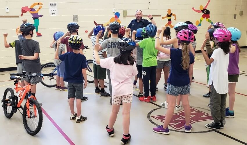 Kids wearing bike helmets in school gym.