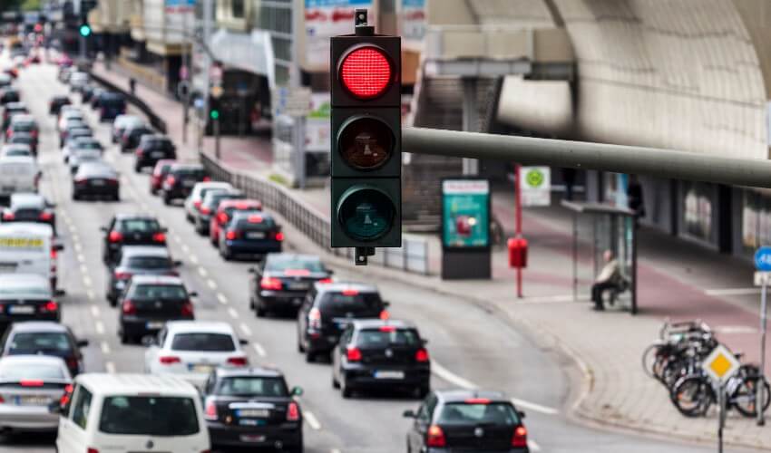Red traffic light during rush hour with cars in the background.