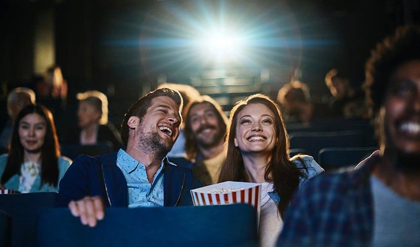 A couple watching a movie and eating popcorn in a cinema