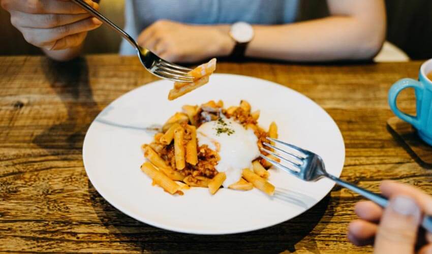 A couple sharing a plate of penne pasta