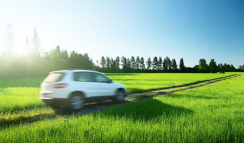 A SUV driving through rural roads, the vehicle is blurred and appear to be in motion.