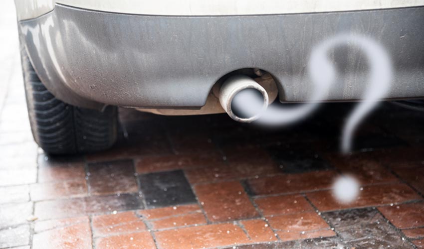 Close up of a car exhaust pipe, with fumes forming a question mark.