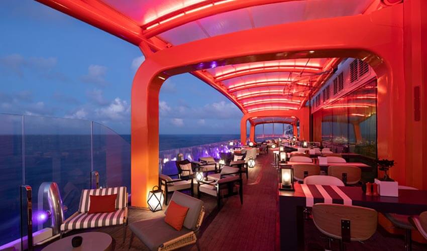 The Magic Carpet restaurant in the evening, overlooking the ocean and illuminated with red LED lighting.
