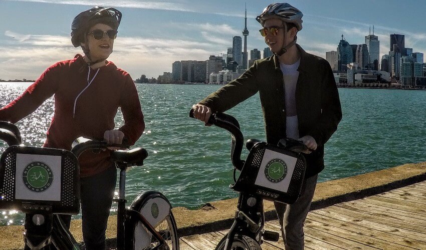 Two happy cyclists using Bike Share at the Toronto Harbour.