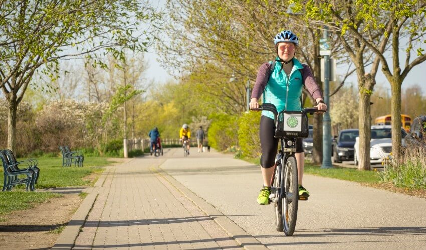 A woman cycling along a trail using a bike share service.