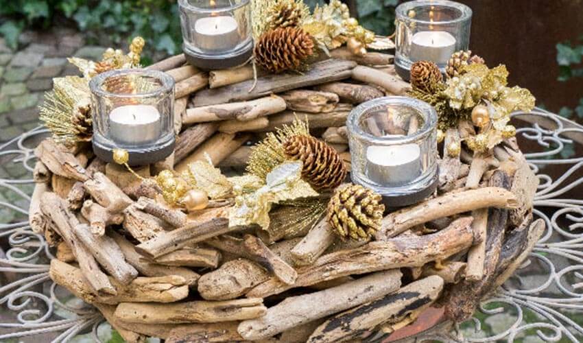 A country chic themed floral arrangement composed of gold pine cones, rustic wood, and candles.