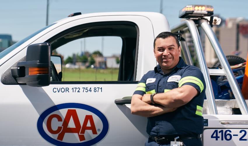 CAA Tow Truck driver smiling in front of his vehicle.