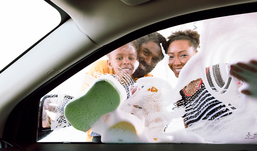 Family seen through car window washing car