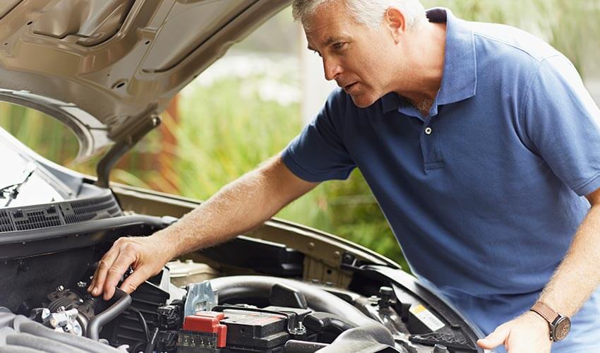 Man checking under hood of car.
