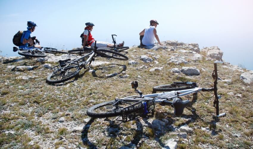 Three cyclists resting on the side of a cliff.