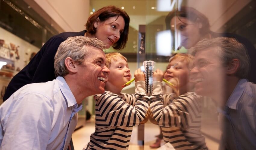Family looking at artifacts in a glass case in a museum.