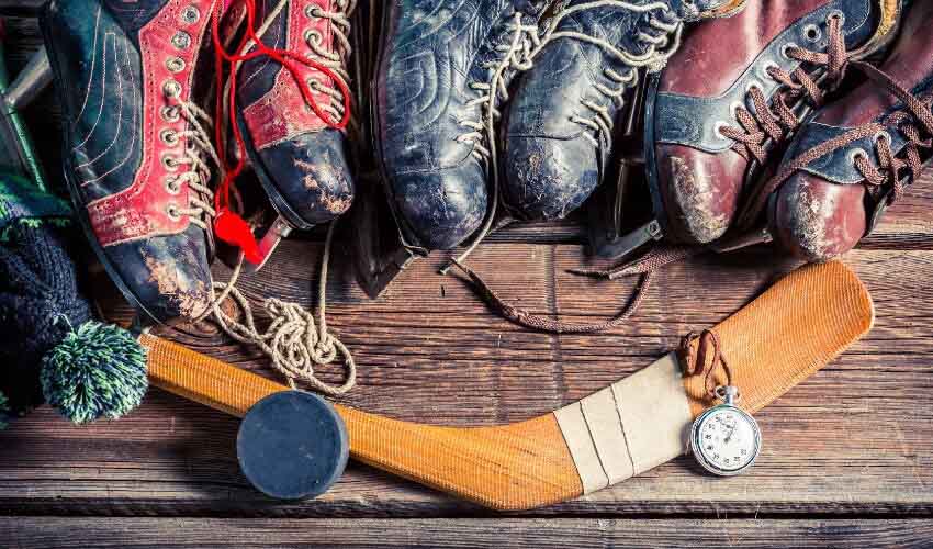 Old fashion skates with a hockey stick.
