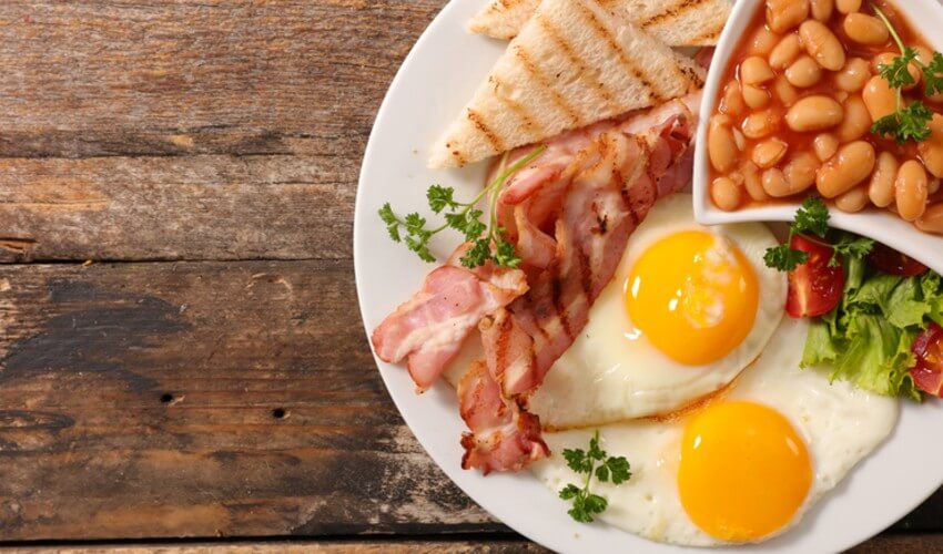 Breakfast plate with eggs, bacon, toast and beans.