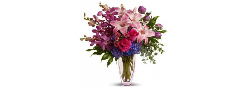 A bouquet of pink orchids with some red roses.