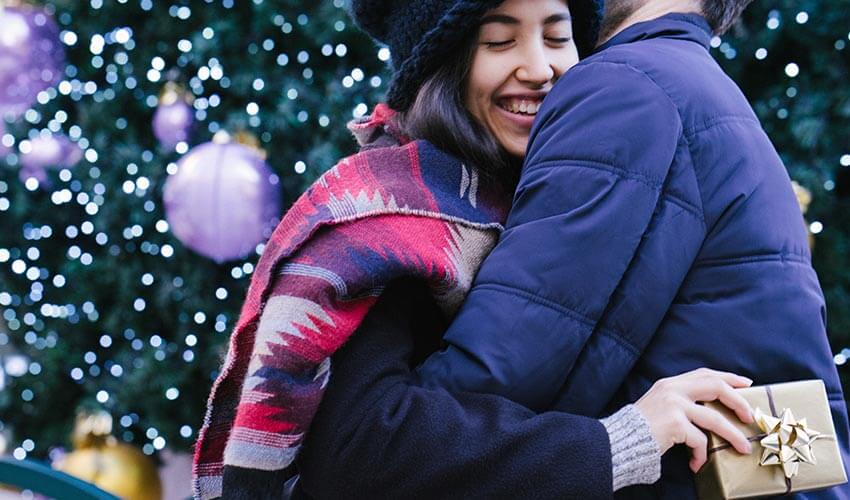 Young couple exchanging Christmas presents in front of Christmas tree.