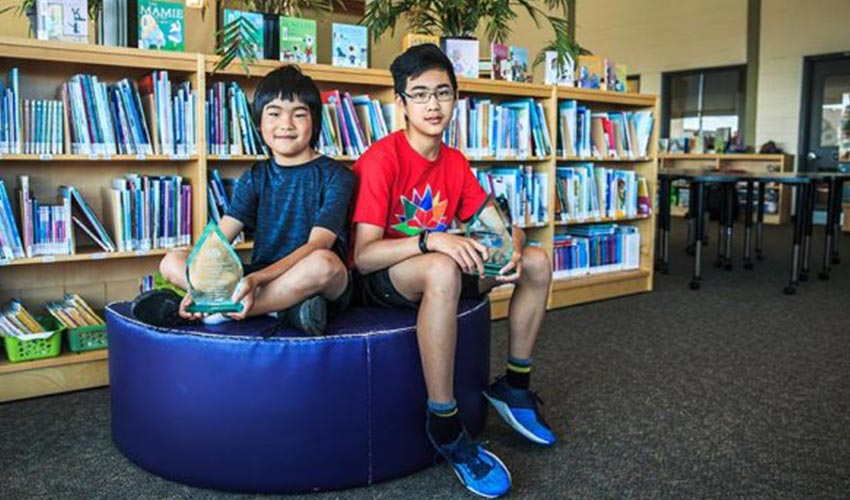 CAA School Safety Patrollers, Justin and Jonathan Zhou sitting in a library.