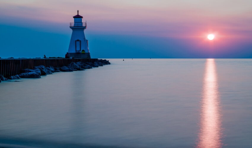 Lighthouse by Lake Huron against a sunset sky.