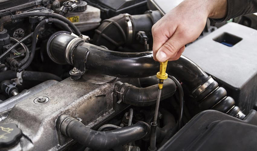 A hand pulling out dipstick to check engine oil level.