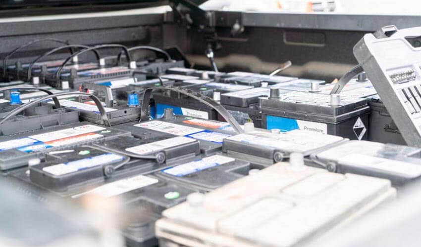A bunch of car batteries inside the flatbed of a pickup truck.