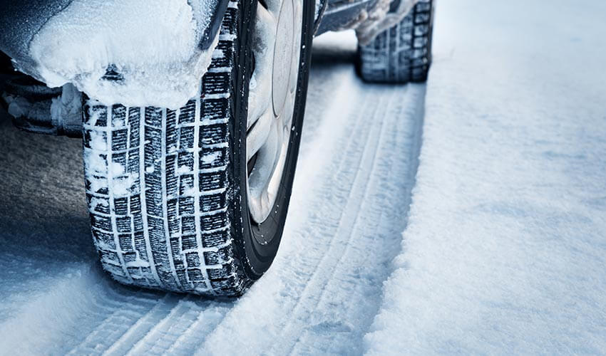 Closeup of car tires in winter on the road covered with snow.