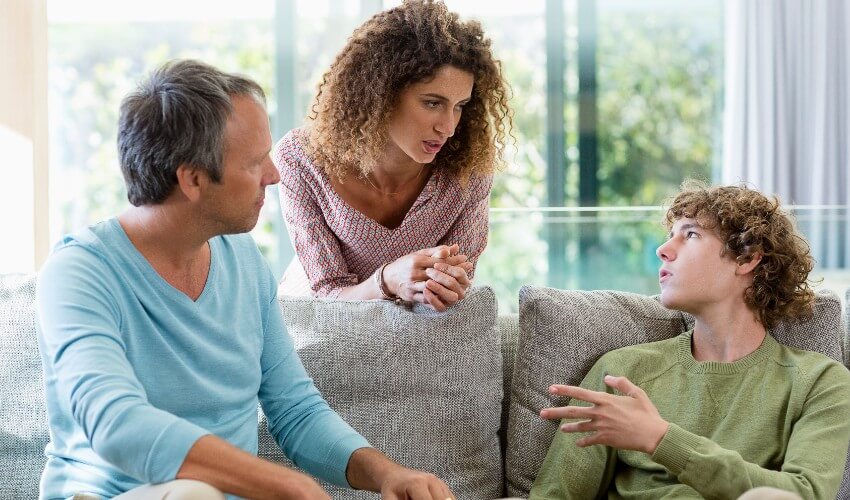 Happy family talking in a living room at home.
