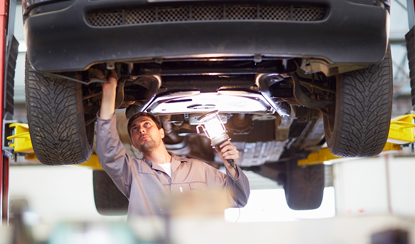 Mechanic checking beneath car on hoist.
