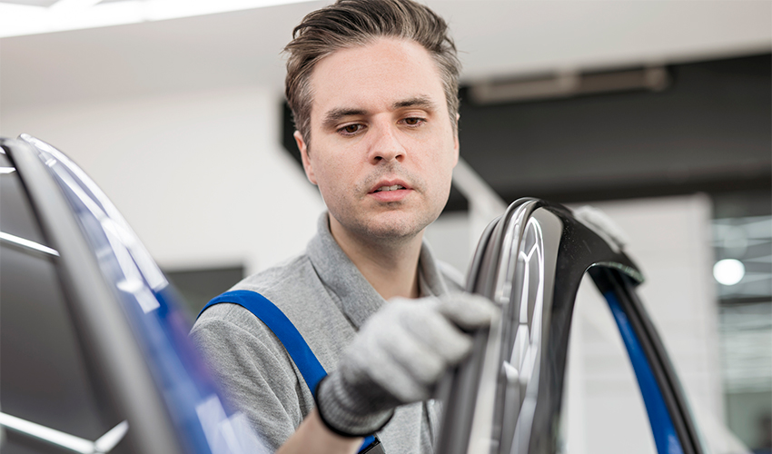 Technician checking weatherstripping on car door.