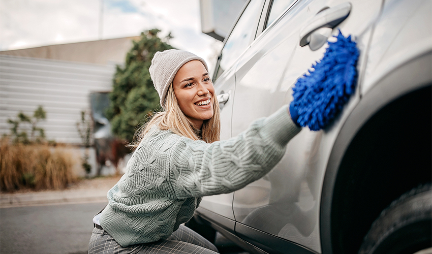 Woman buffing car with shammy cloth.