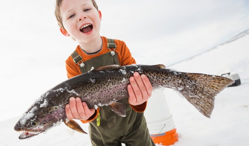 Boy holding fish in snow.